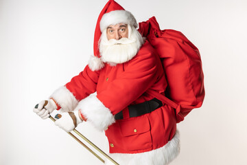 Profile of Santa Claus on a white background with ski poles and a bag on his back. Active lifestyle with winter sports White background.