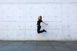 © wernerimages - woman in black clothes jumping in front of grey wall
