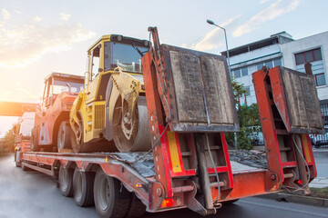 Wall Mural - Heavy road equipment asphalt compactor loaded and transported on a truck trailer