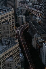 Canvas Print - Vertical shot of the cars driving on the narrow road between the modern buildings