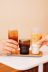 Sticker - Vertical shot of ice latte, cold brew and cold brew tonic on a tray on the white table