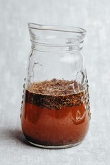 Sticker - Vertical shot of a glass jug with water and a grounded coffee on a gray background