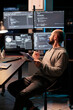 © DC Studio - Web developer comparing data on papers and multple screens, working late at night on IT programming analysis. Coder looking at html script and information on clipboard files in office.