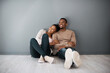 © T Hover/peopleimages.com - Apartment, love and couple on floor with wall background relax, rest and bond after moving in new home together. Real estate, dating and young black couple in living room thinking of house design