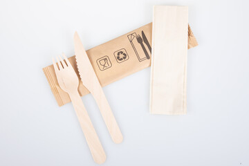 wood tableware wooden fork knife and recycled napkin on recyclable packaging isolated on white background