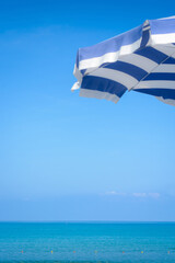 Background with blue sky, sea, with blurry part of parasol with copy space