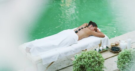 Canvas Print - Pool, massage and stone with woman at spa resort for luxury, skincare and relax on Bali vacation. Travel destination, tropical and peace with customer on table at villa for detox, zen and beauty