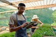 © StratfordProductions - Young multiracial couple in aprons using digital tablet while examining plants in plant nursery