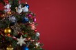 Closeup of cute toys and garlands on the Christmas tree on a red background