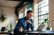 © bnenin - Smiling businessman using a laptop, working at the office, holding his glasses.