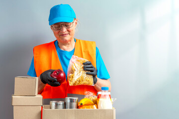 Wall Mural - Help Collection Center, free food distribution. Volunteers wearing uniform green caps, t-shirts, orange vests prepare a food package grocery set for in-need people, sort, collect food donation boxes