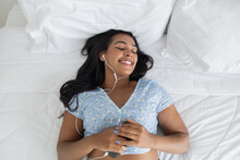 Young Black Woman In Her Bed Listening To Music With Headphones At Home. Feel Good