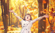 Portrait Of Cute Girl Standing In Autumn Forest