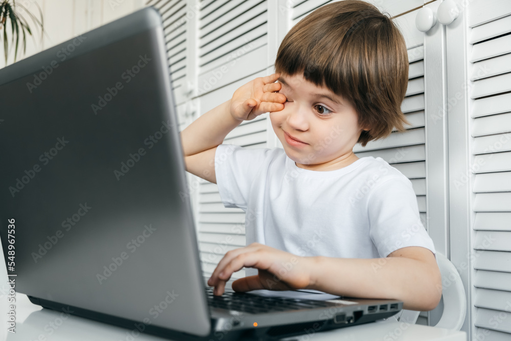 5 year boy uses laptop, closed eyes, tired, headached. Student abuse ...