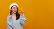 © NaMong Productions - Beautiful young Asian woman pointing up to copy space and smile face isolated on yellow background. Teenager girl looking at empty space for text advertisement..