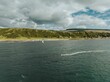 View of the sea with a person kitesurfing near the green shore. Scotland, UK.