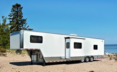 white toy hauler travel trailer camping on the sandy shore of lake superior