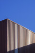 © Prapat - Brown Corrugated Steel Wall of Warehouse Building with sunlight on surface with blue clear sky background in Vertical frame