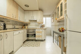 Fototapeta  - Kitchen of a vacation rental home with built-in appliances, small appliances on the countertop, and a cozy fruit bowl filled with fruit