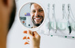 © Hunterframe - Satisfied man looks in the mirror and smiles after treatment at the dentist