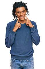 Wall Mural - Young african american man wearing casual winter sweater smiling with open mouth, fingers pointing and forcing cheerful smile