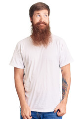 Wall Mural - Handsome young red head man with long beard wearing casual white tshirt smiling looking to the side and staring away thinking.