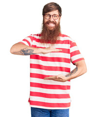 Sticker - Handsome young red head man with long beard wearing casual clothes gesturing with hands showing big and large size sign, measure symbol. smiling looking at the camera. measuring concept.