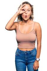 Wall Mural - Beautiful caucasian woman wearing casual clothes doing ok gesture shocked with surprised face, eye looking through fingers. unbelieving expression.