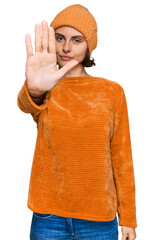 Poster - Young hispanic woman wearing casual clothes and wool cap doing stop sing with palm of the hand. warning expression with negative and serious gesture on the face.