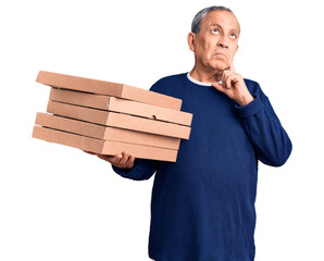 Wall Mural - Senior handsome man holding pizza boxes serious face thinking about question with hand on chin, thoughtful about confusing idea