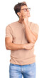 © Krakenimages.com - Young handsome man wearing casual clothes and glasses with hand on chin thinking about question, pensive expression. smiling with thoughtful face. doubt concept.