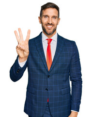 Poster - Handsome man with beard wearing business suit and tie showing and pointing up with fingers number three while smiling confident and happy.