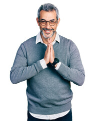 Poster - Middle age hispanic with grey hair wearing glasses praying with hands together asking for forgiveness smiling confident.