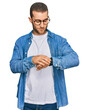 Young caucasian man wearing casual clothes checking the time on wrist watch, relaxed and confident