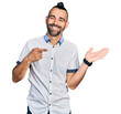 © Krakenimages.com - Hispanic man with ponytail wearing casual white shirt amazed and smiling to the camera while presenting with hand and pointing with finger.