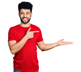 Sticker - Young arab man with beard wearing casual red t shirt amazed and smiling to the camera while presenting with hand and pointing with finger.