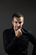 © mikeosphoto - Portrait of pensive man in a black shirt on a dark background. Young caucasian dark-haired man