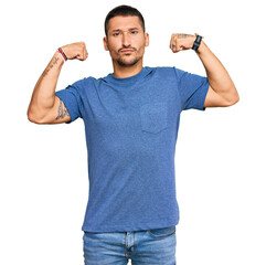 Canvas Print - Handsome man with tattoos wearing casual clothes showing arms muscles smiling proud. fitness concept.