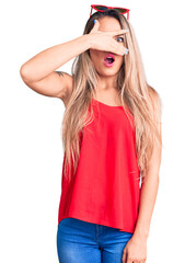 Canvas Print - Young beautiful blonde woman wearing sleeveless t-shirt and sunglasses peeking in shock covering face and eyes with hand, looking through fingers with embarrassed expression.