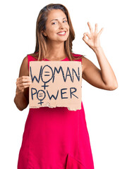 Sticker - Middle age hispanic woman holding woman power banner doing ok sign with fingers, smiling friendly gesturing excellent symbol