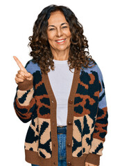 Sticker - Middle age hispanic woman wearing casual clothes with a big smile on face, pointing with hand and finger to the side looking at the camera.