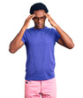 © Krakenimages.com - African handsome man wearing casual clothes and glasses with hand on head for pain in head because stress. suffering migraine.