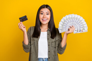 Sticker - Photo of impressed ecstatic cheerful girl with brunette hair wear gray shirt hold debit card money isolated on yellow color background