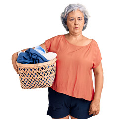 Canvas Print - Senior woman with gray hair holding laundry basket thinking attitude and sober expression looking self confident