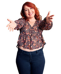 Poster - Young beautiful redhead woman wearing casual t-shirt looking at the camera smiling with open arms for hug. cheerful expression embracing happiness.