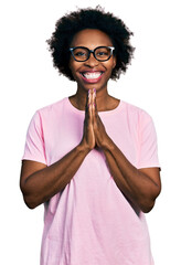 Poster - African american woman with afro hair wearing casual clothes and glasses praying with hands together asking for forgiveness smiling confident.