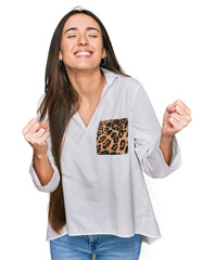 Sticker - Young hispanic girl wearing casual clothes very happy and excited doing winner gesture with arms raised, smiling and screaming for success. celebration concept.