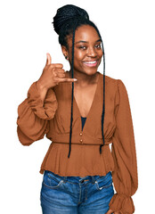 Wall Mural - Young african american woman wearing casual clothes smiling doing phone gesture with hand and fingers like talking on the telephone. communicating concepts.