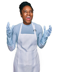 Wall Mural - Young african american woman wearing apron crazy and mad shouting and yelling with aggressive expression and arms raised. frustration concept.