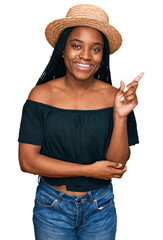 Canvas Print - Young african american woman wearing summer hat smiling happy pointing with hand and finger to the side